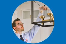 Electrician installing light fixture
